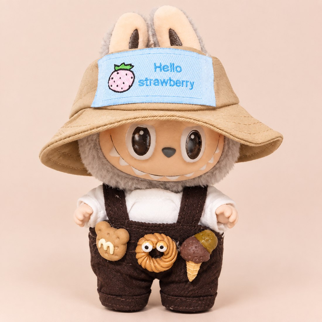 Plush doll wearing brown overalls with strawberry embroidery