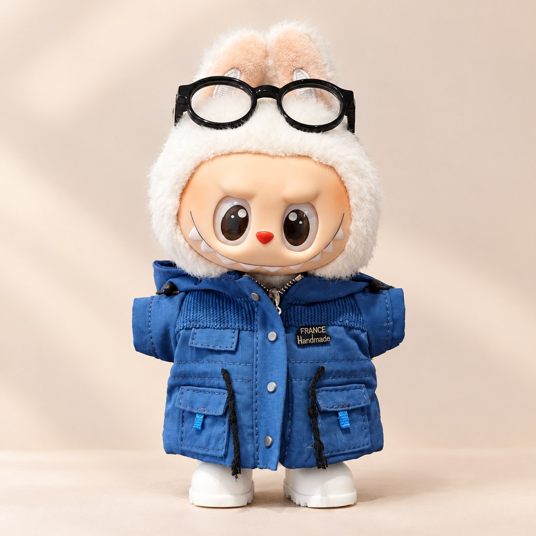 Blue quilted puffer jacket with fur hood on a plush doll